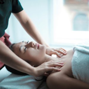 A serene spa massage session with a woman relaxing on a table, receiving a calming neck massage.